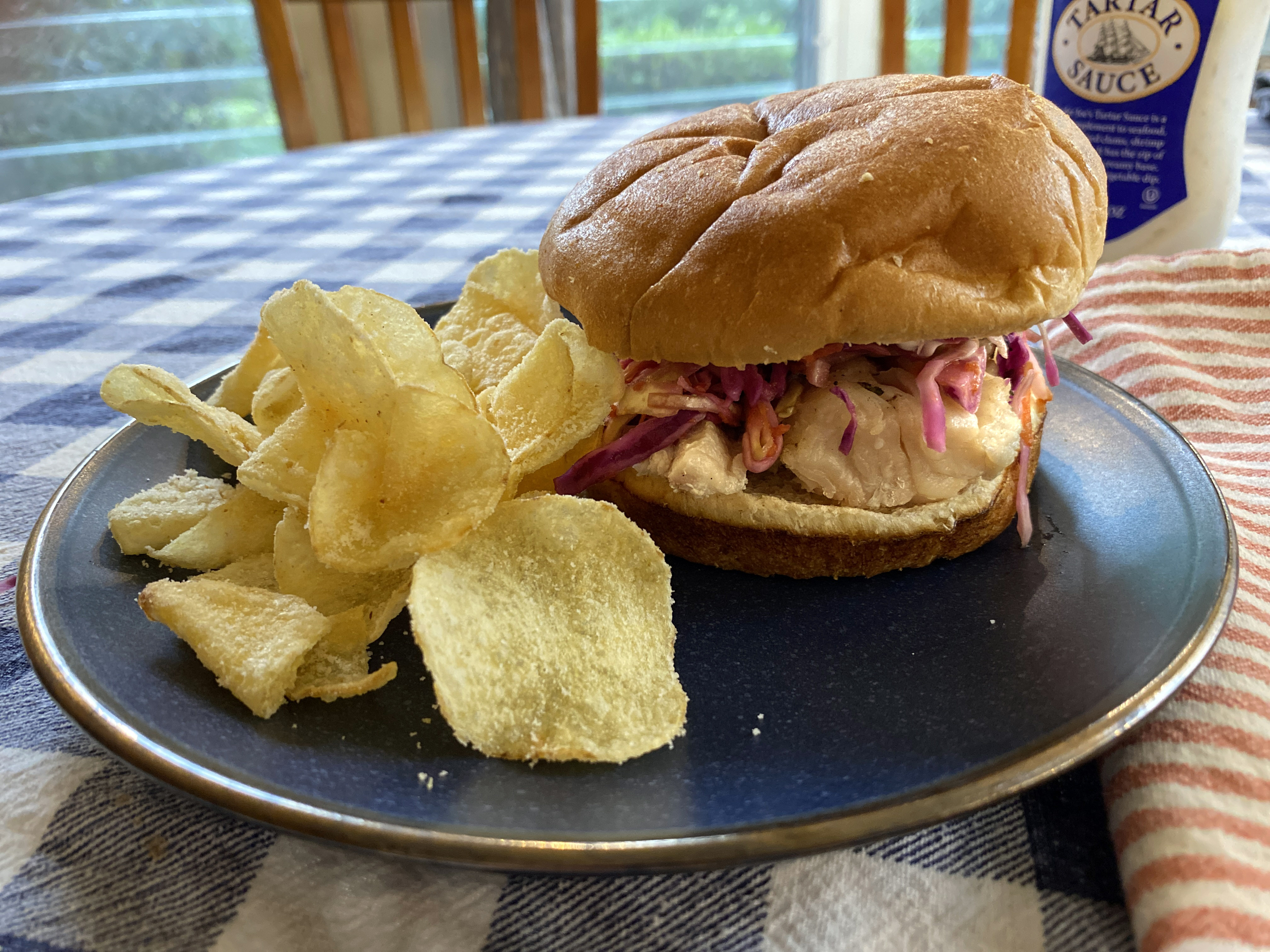 Sandwich sits on plate with chips